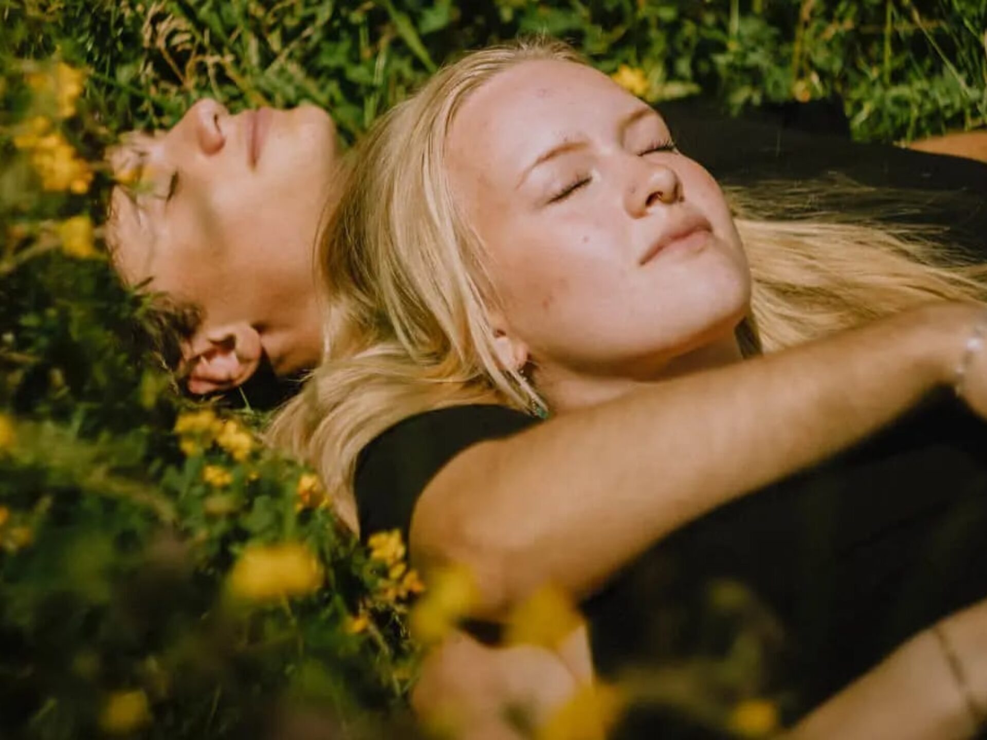 Nicoline ligger i en græseng sammen med en dreng