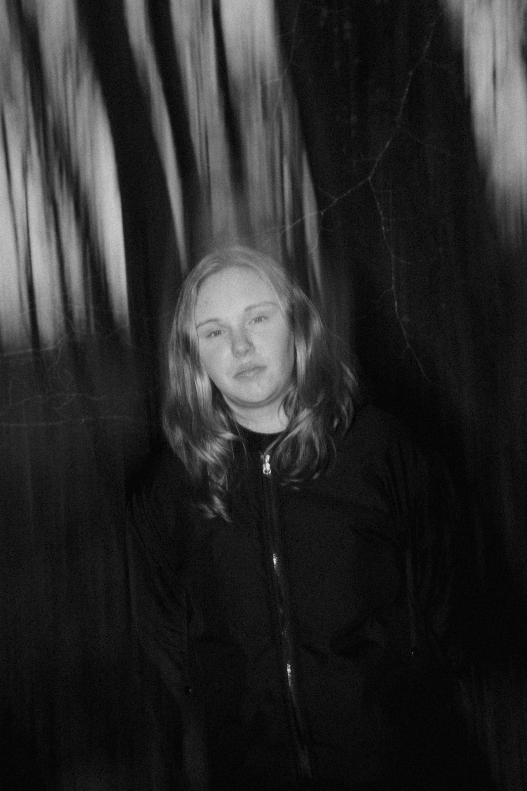 Dikte står ude i en skov. Billedet er sort/hvid og lidt slørret.