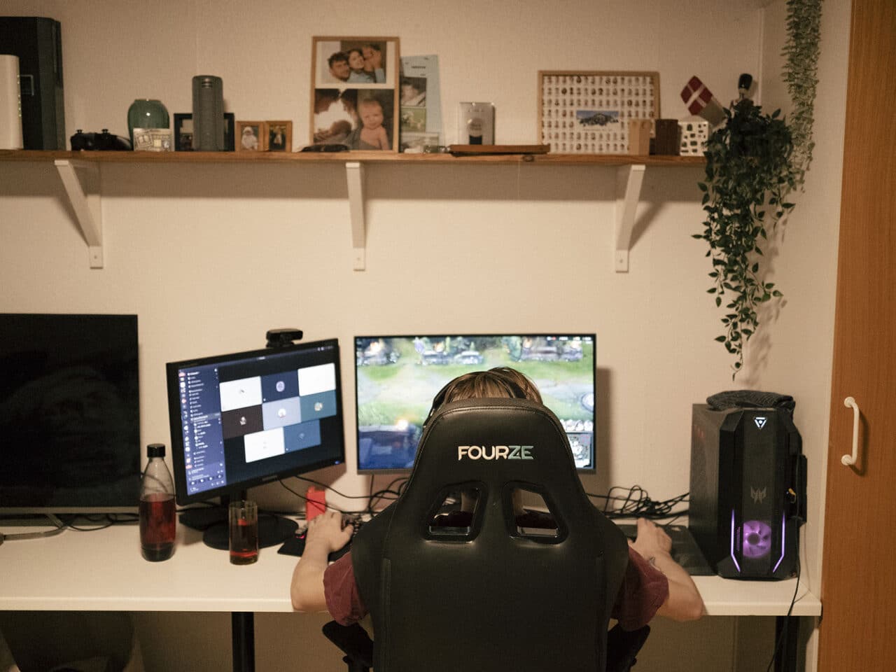 Sebastian sidder i en gaminstol foran et skrivebord med to skærme.
