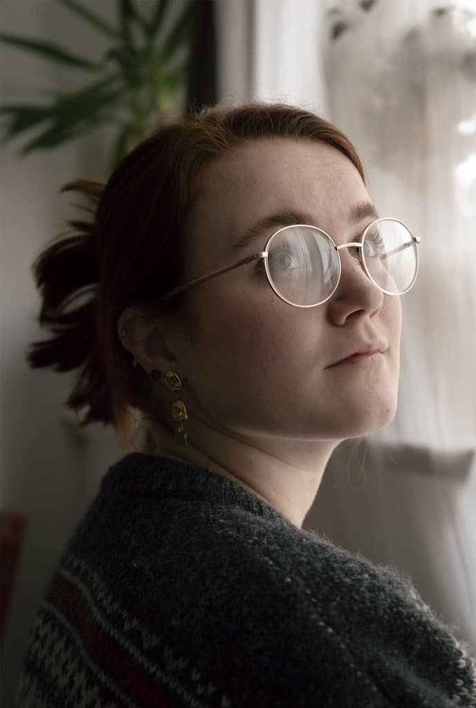 Nicoline sidder og kigger op til højre fjernt ud i luften